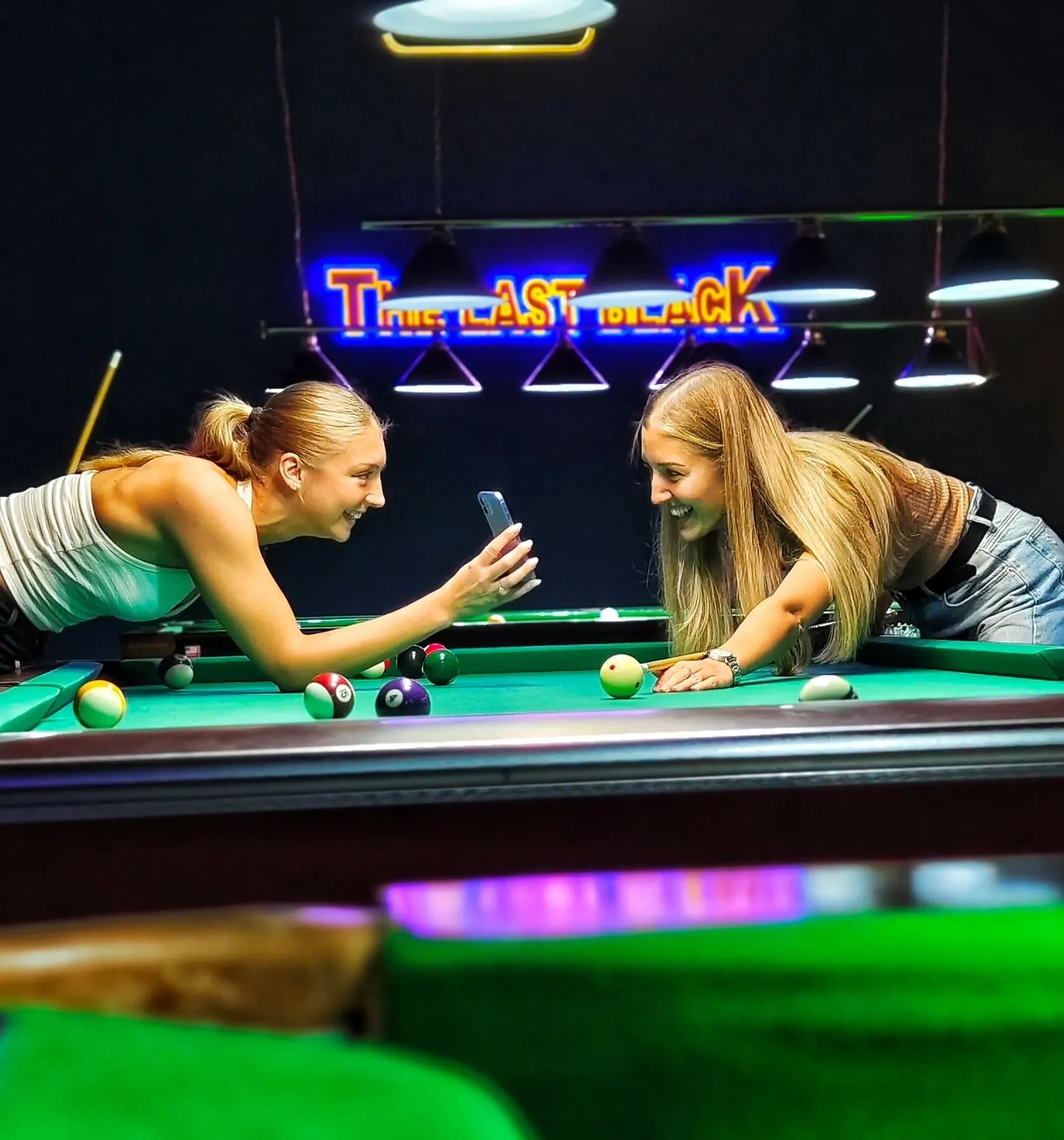 Two friends at the table under the neon sign
