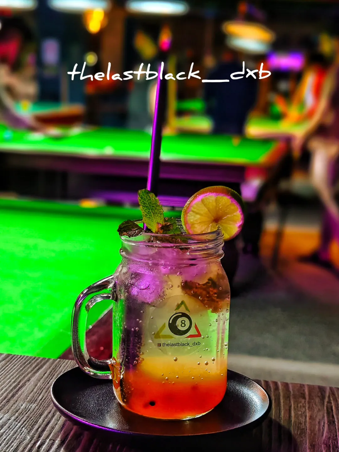 A mojito on the rail of a pool table